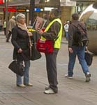man selling big issue magazine talking to woman in city street adelaide south australia