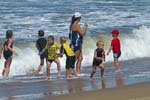 group of children boys and girls playing in waves at australian beach